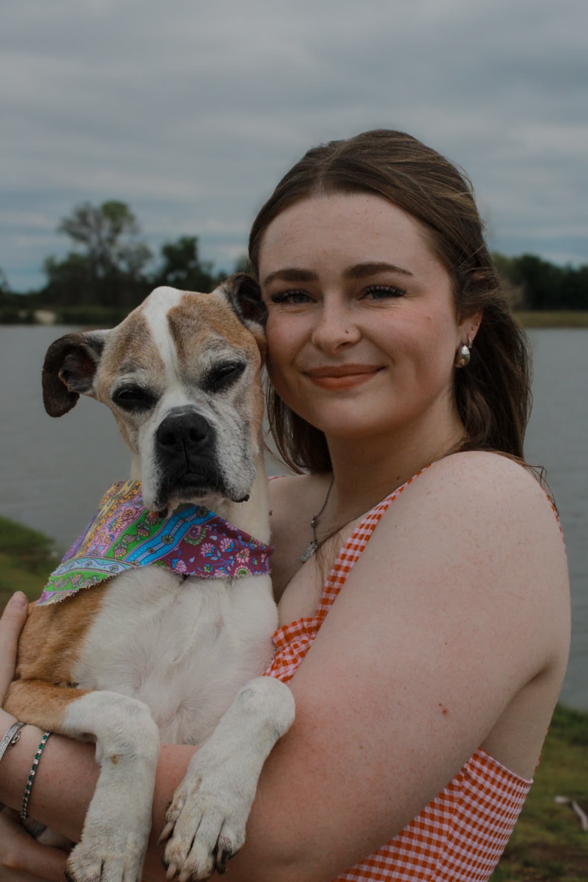 A woman holding her dog close in an open field.