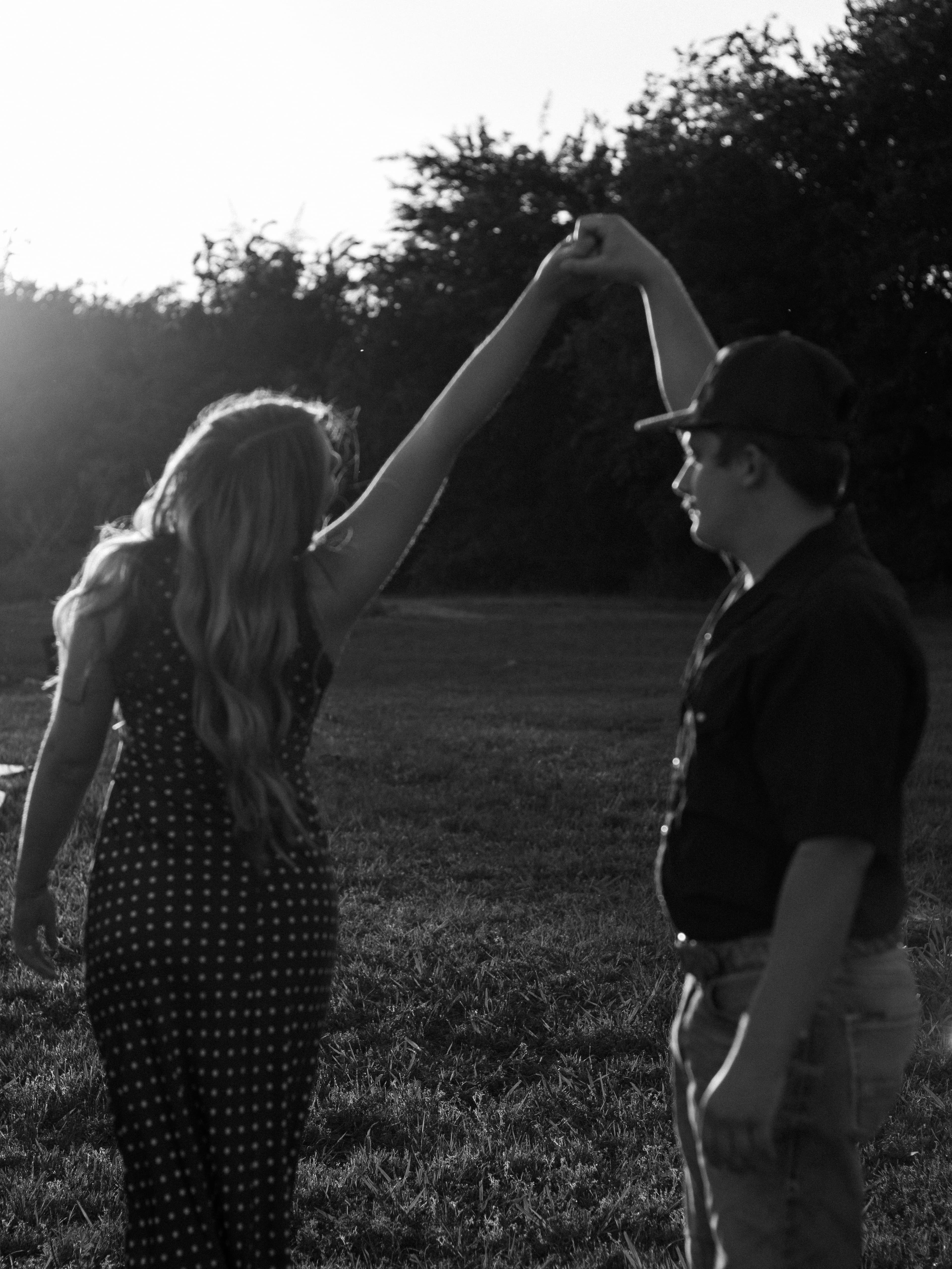 A black-and-white photograph of a couple dancing in a sunlit field.