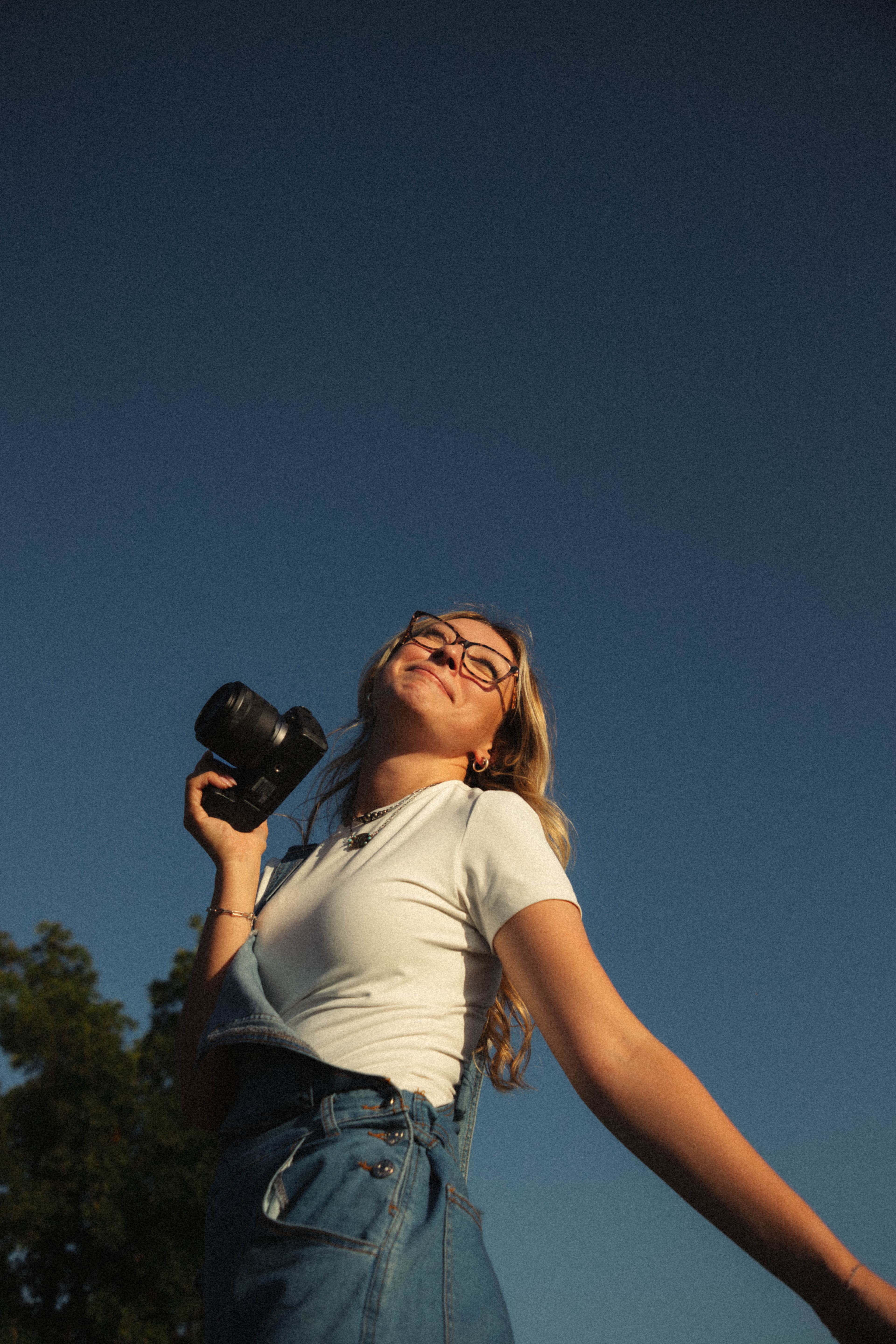 Rachel Skaggs holding her camera beneath a blue sky.